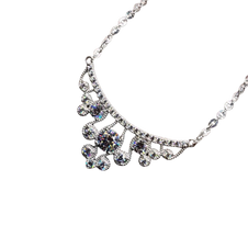 Silver necklace with floral design and clear stones on a white background