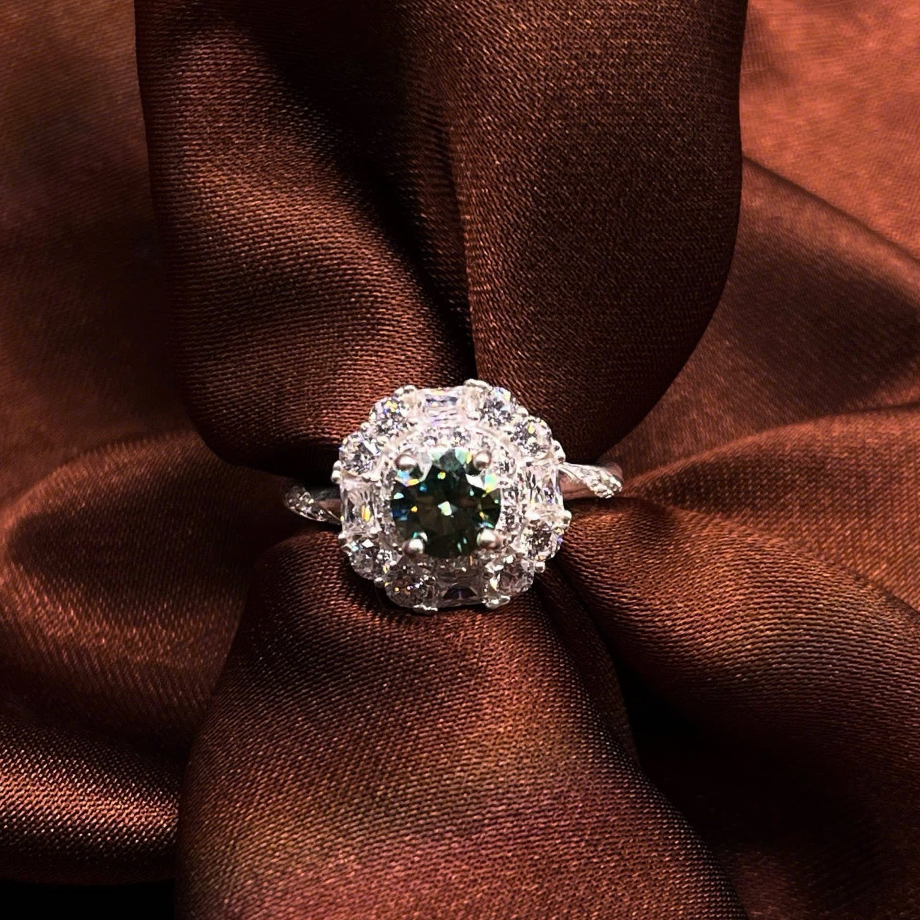 Silver ring with a green gemstone on brown fabric