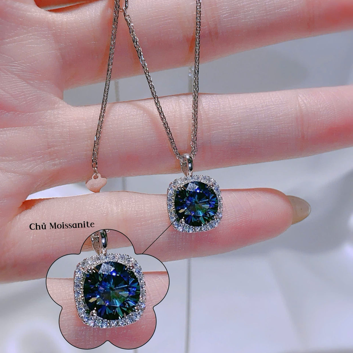 Blue gemstone earrings held between fingers with a blurred background