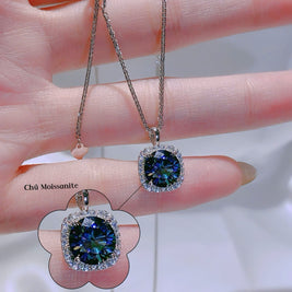Blue gemstone earrings held between fingers with a blurred background