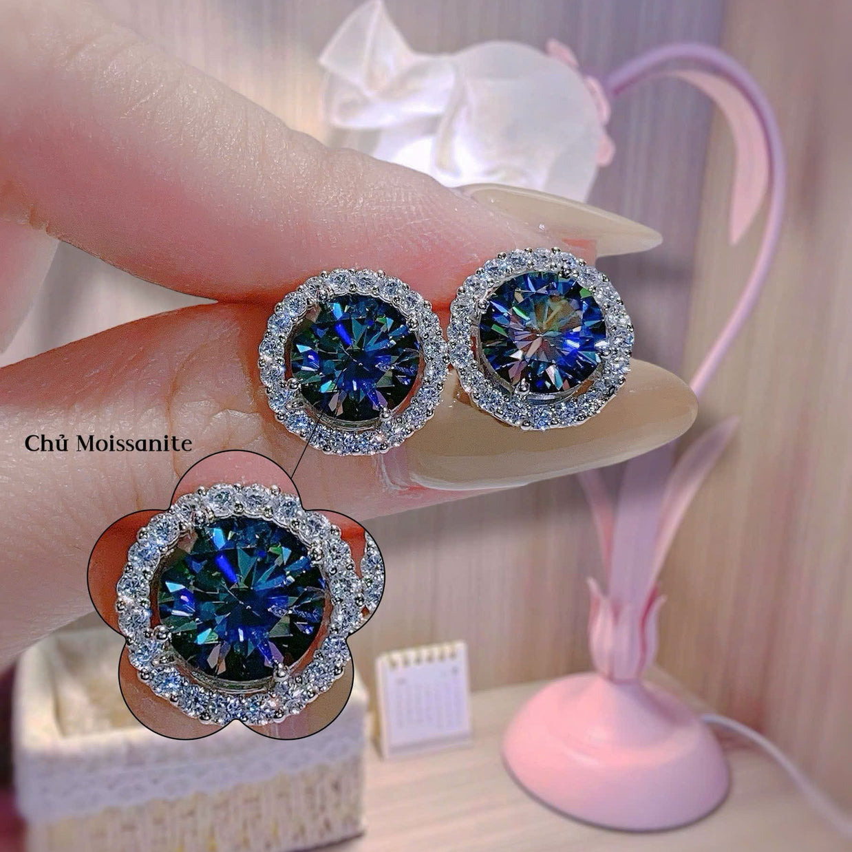 Blue gemstone earrings held by a hand with a blurred background