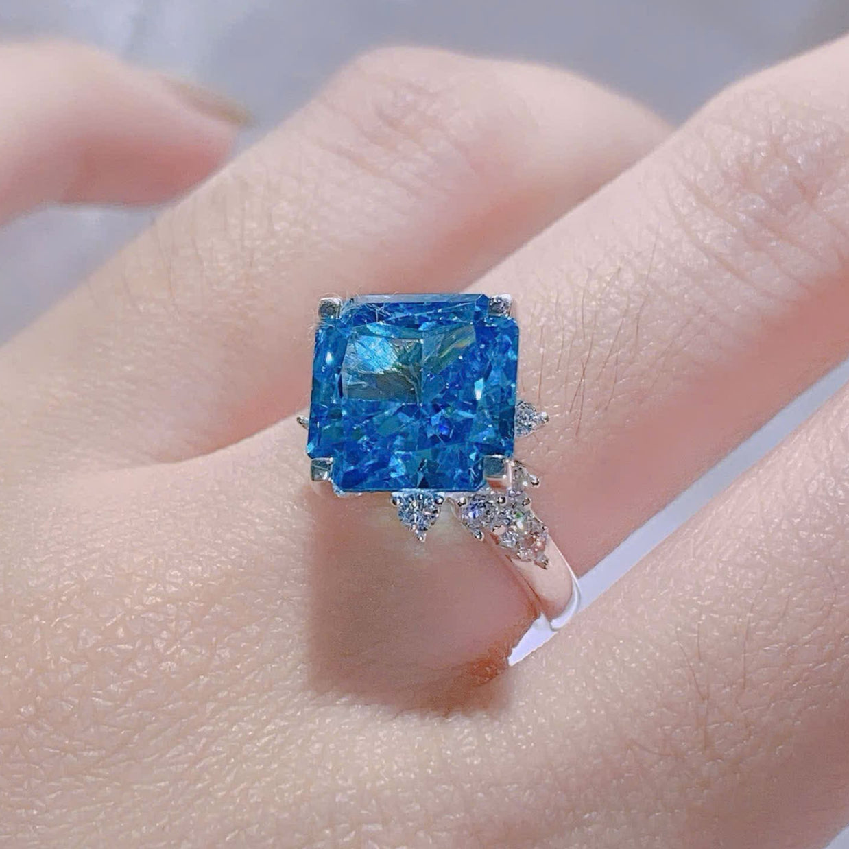 Blue gemstone ring on a hand with a blurred background