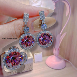 Chu Moissanite earrings held by a hand with a soft background