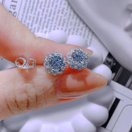 Close-up of a hand holding two pairs of earrings against a blurred background