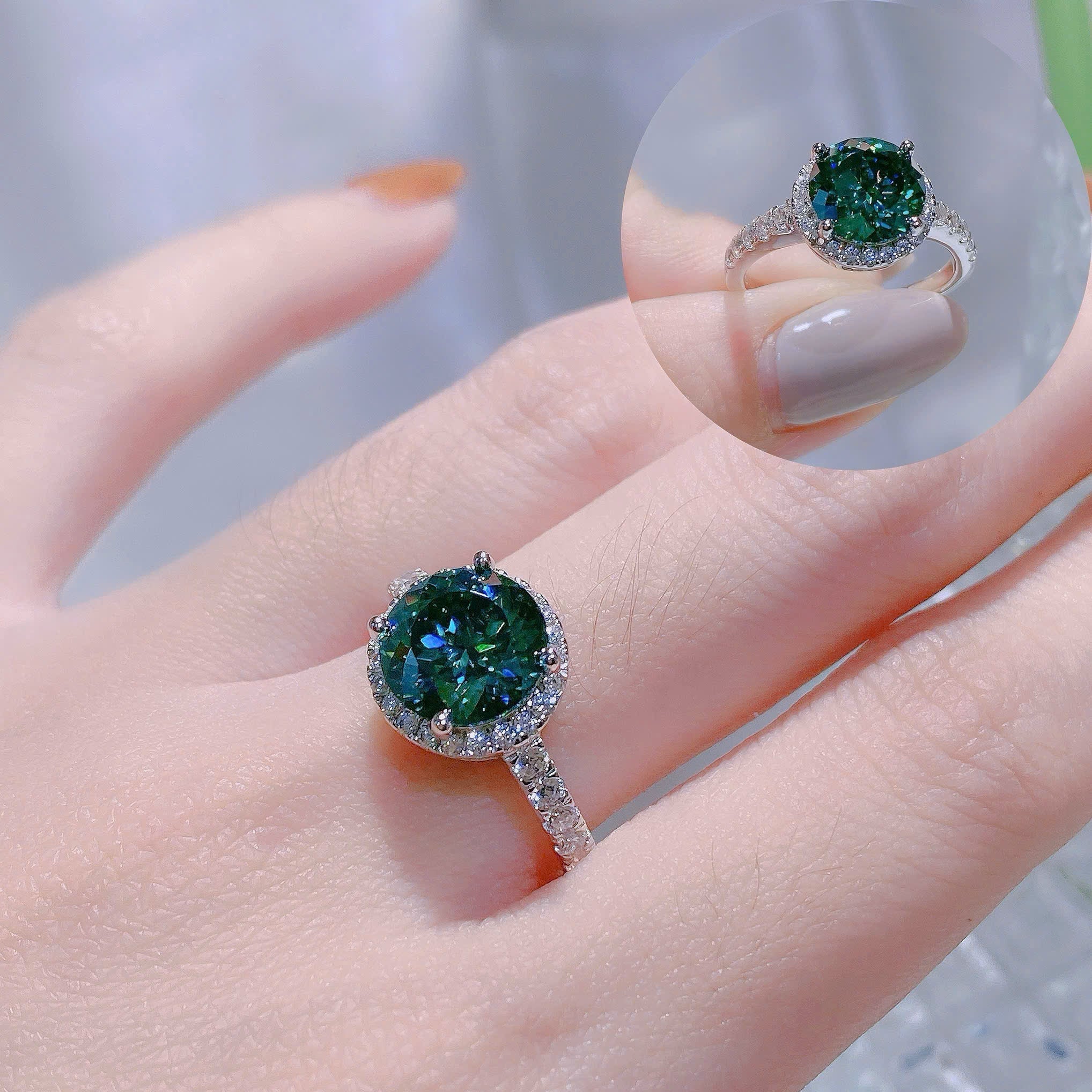 Close-up of a hand wearing a green gemstone ring with a blurred background