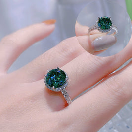Close-up of a hand wearing a green gemstone ring with a blurred background