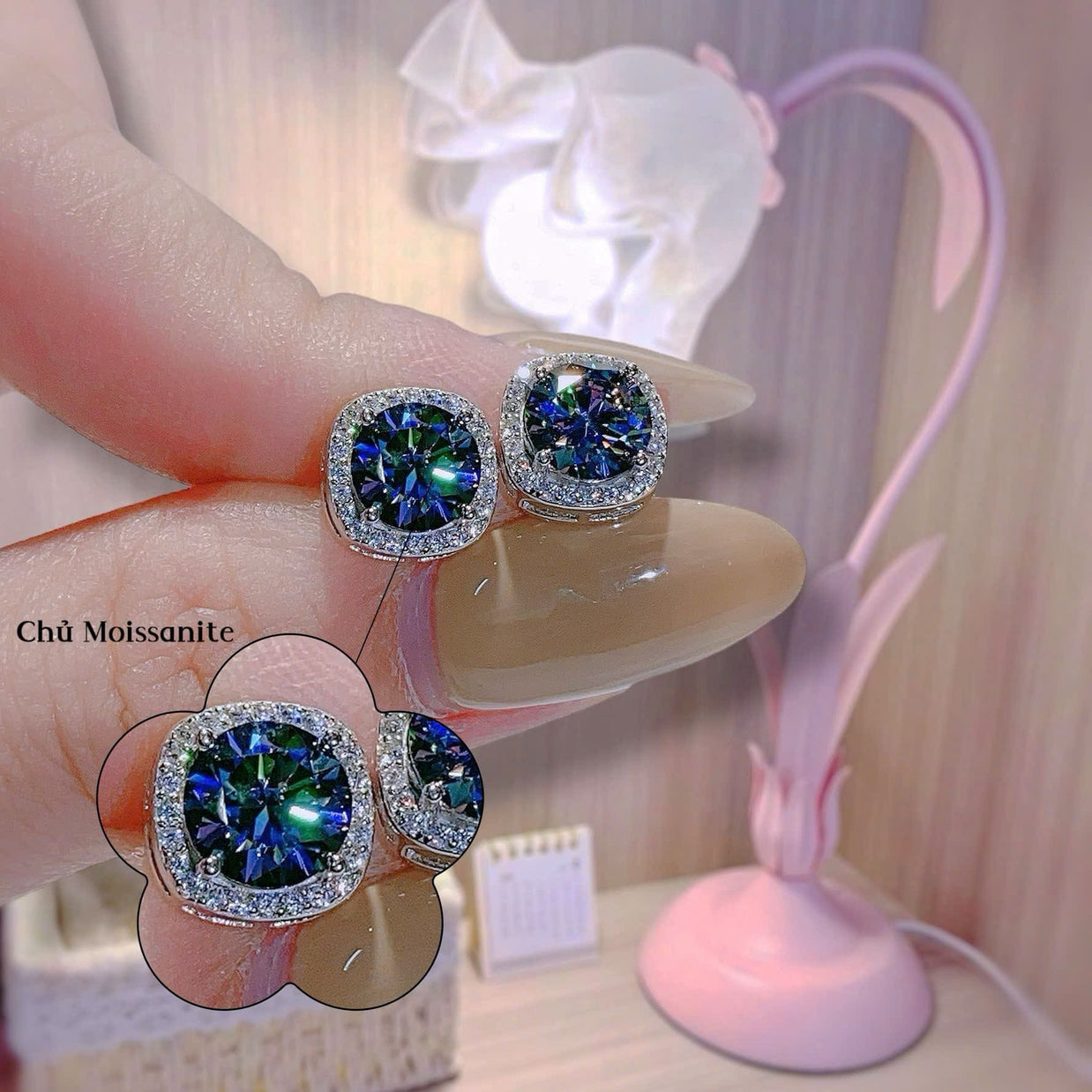 Close-up of a pair of gemstone earrings held between fingers with a blurred background.