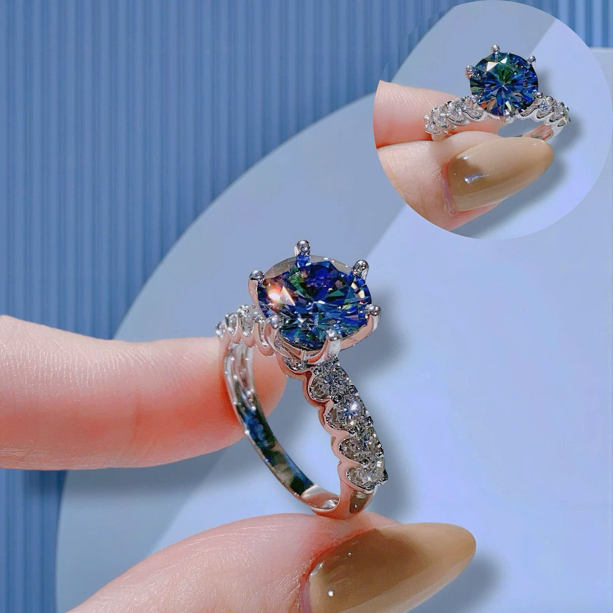 Close-up of a ring with a blue gemstone on a finger against a light blue background