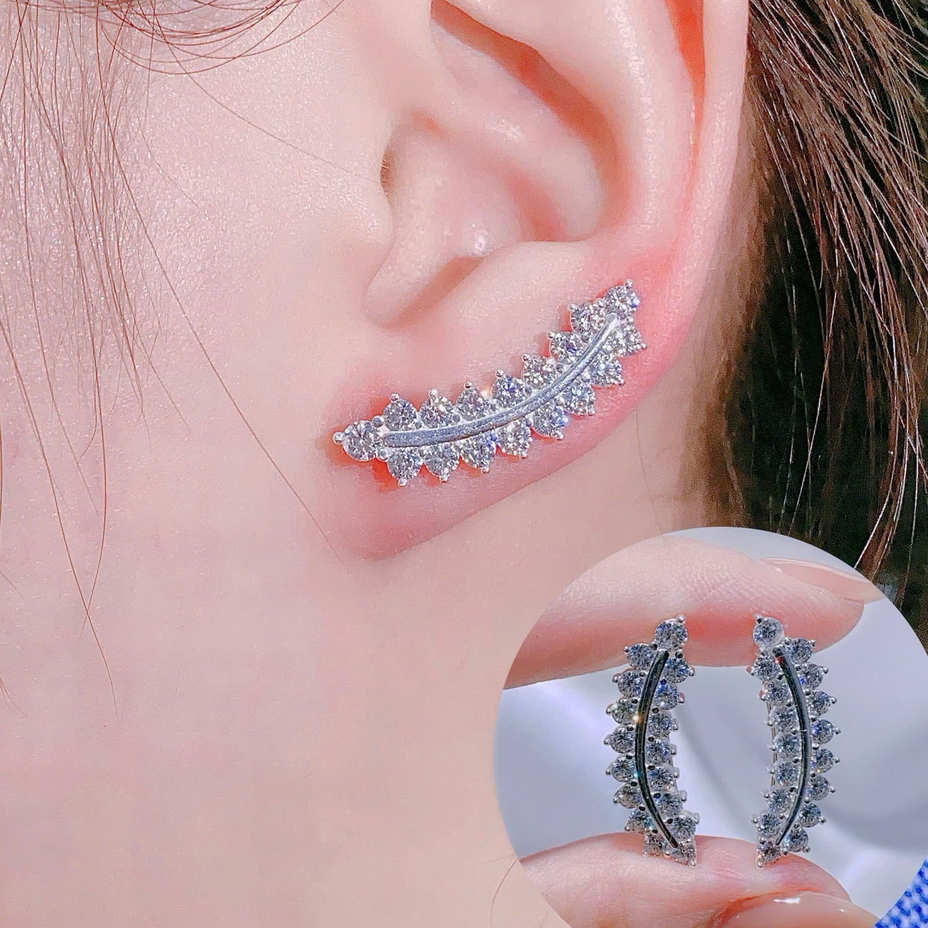 Close-up of an ear wearing a decorative earring with a matching earring held in hand.