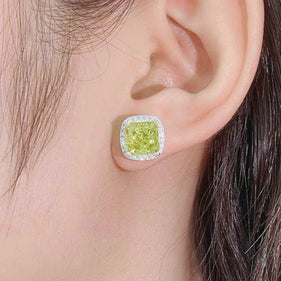 Close-up of an ear wearing a green gemstone earring with a plain background