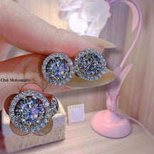 Close-up of diamond earrings held by a hand with a blurred background