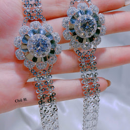 Delicate silver earrings with gemstones held between fingers against a neutral background