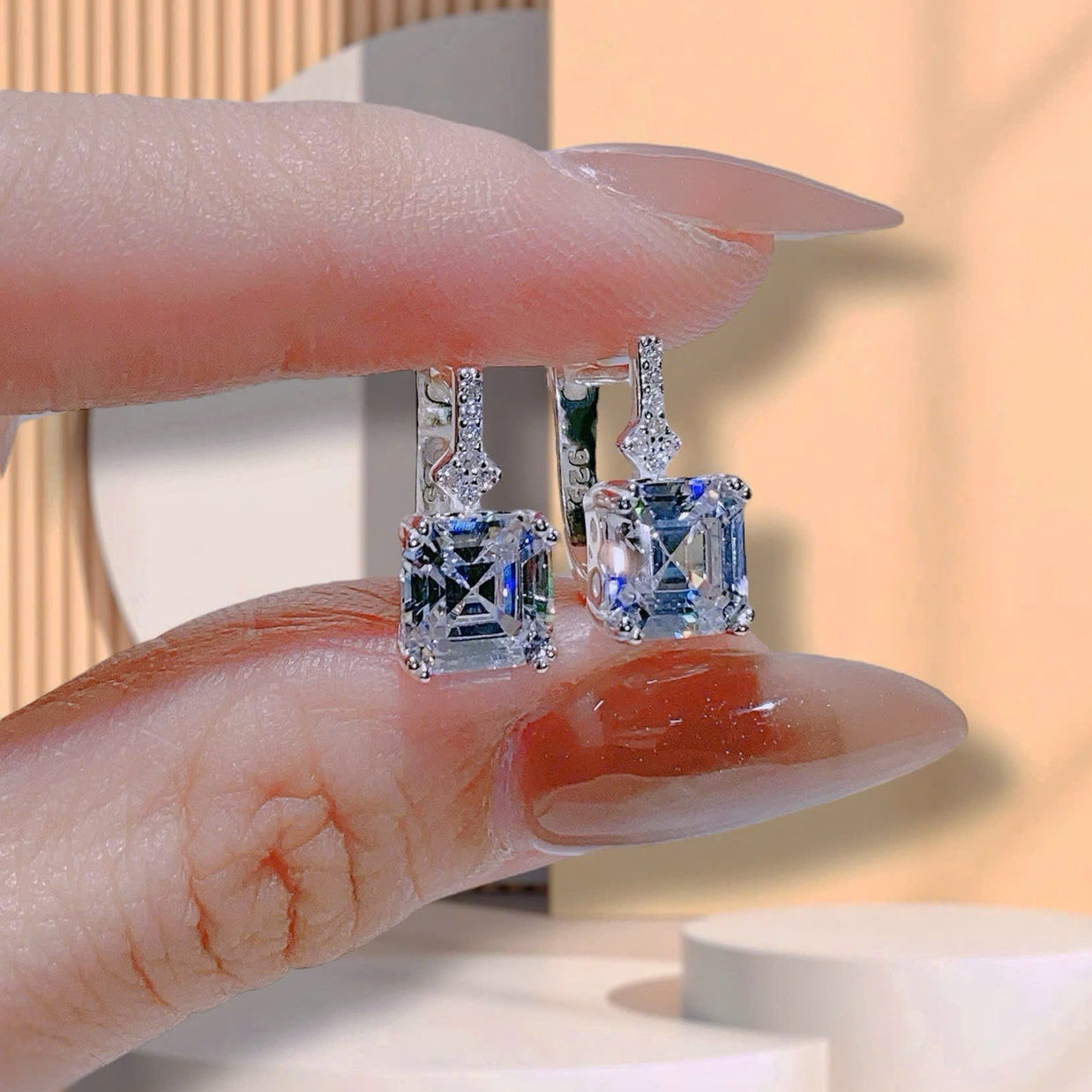 Diamond earrings displayed on a finger with a soft background