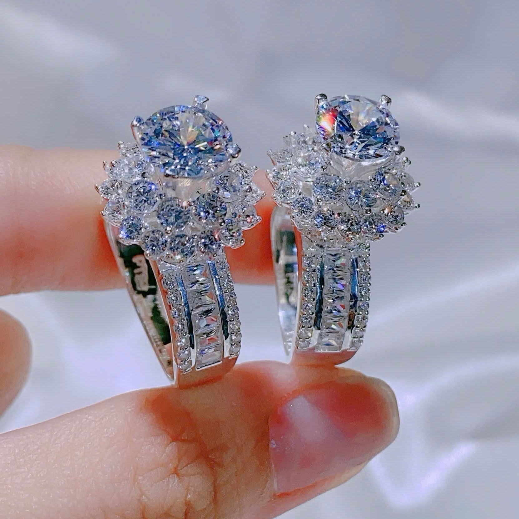 Diamond earrings held between fingers against a blurred background