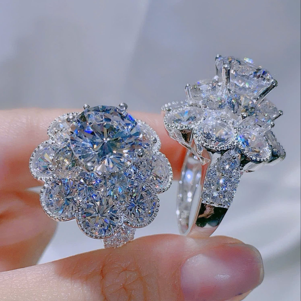 Diamond earrings held between fingers against a blurred background