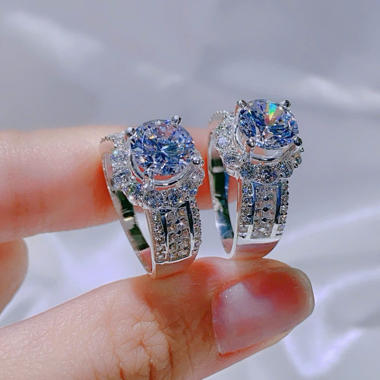 Diamond earrings held between fingers with a blurred background
