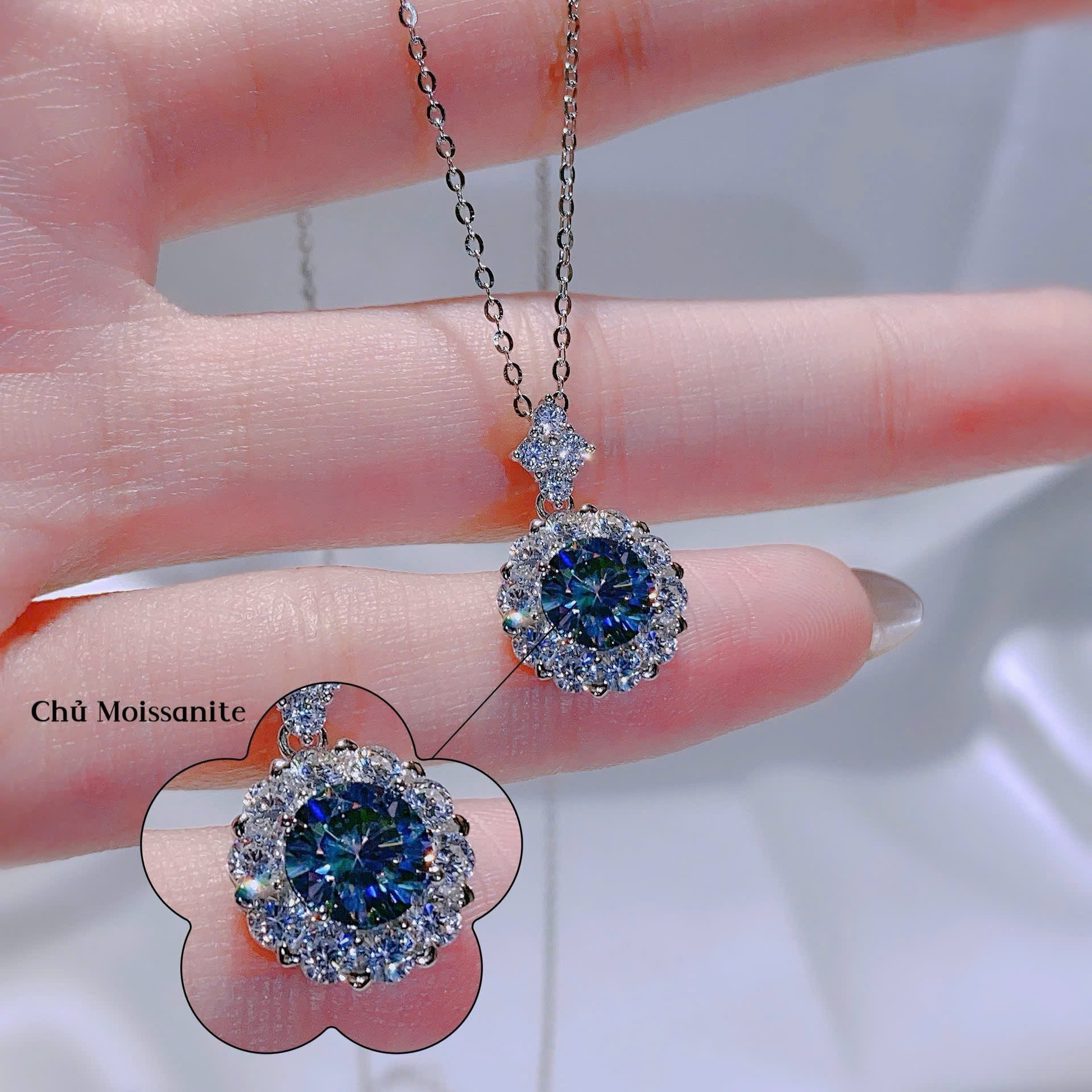 Diamond earrings held by a hand with a blurred background