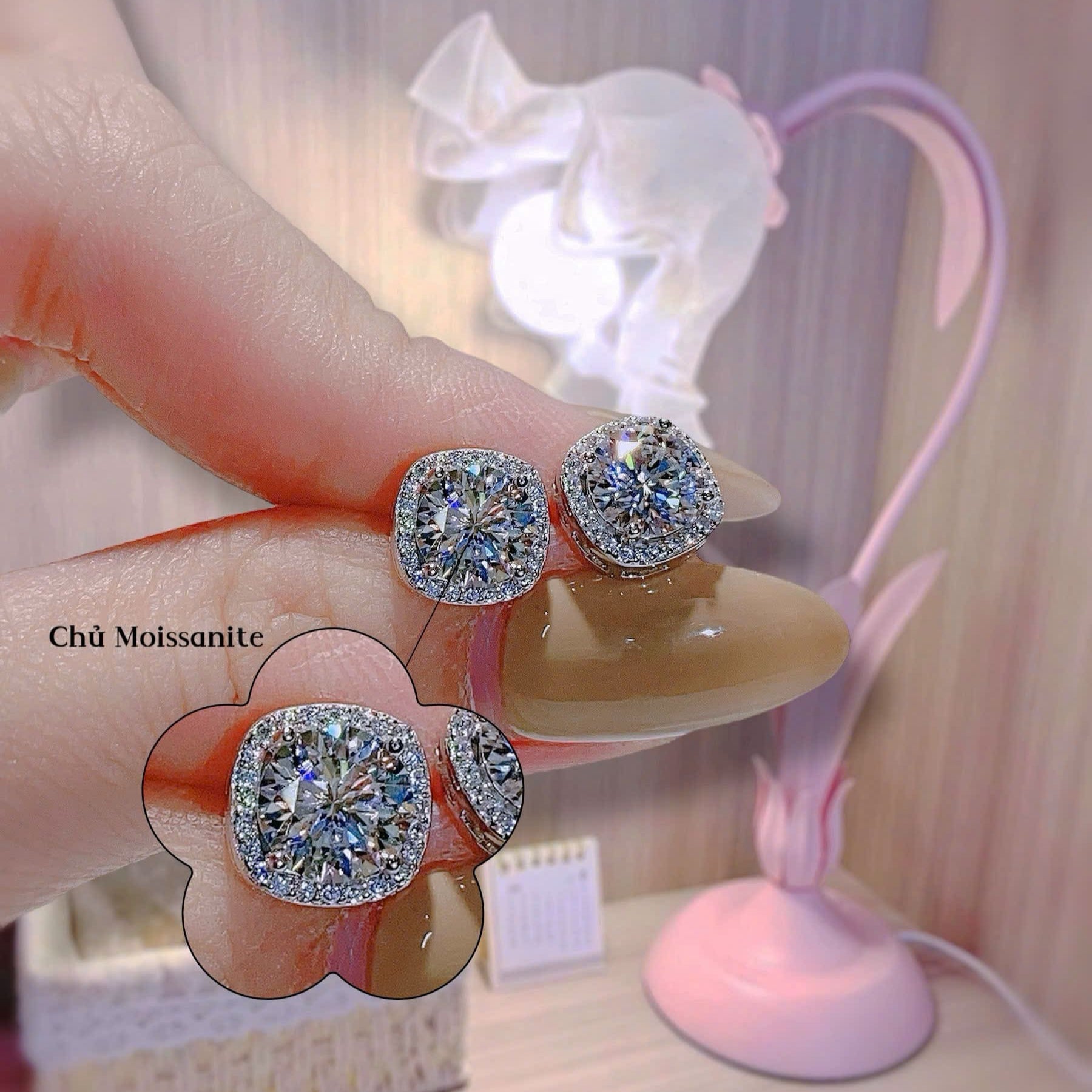 Diamond earrings held by a hand with a blurred background
