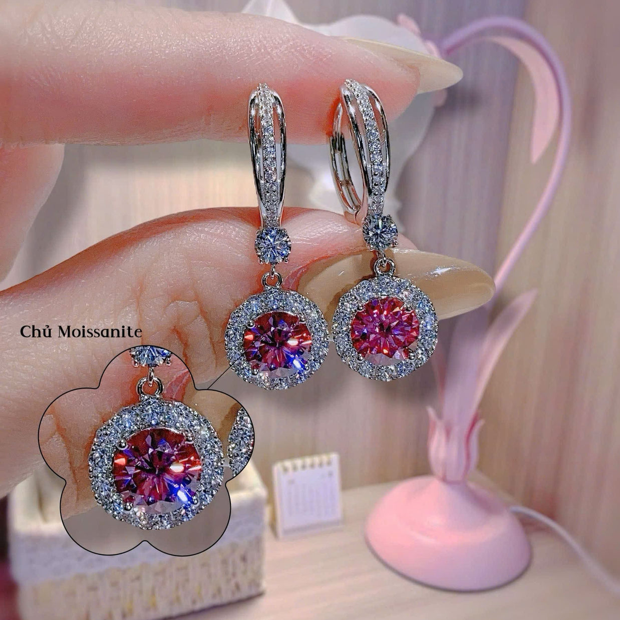 Diamond earrings with red gemstones held by a hand against a blurred background