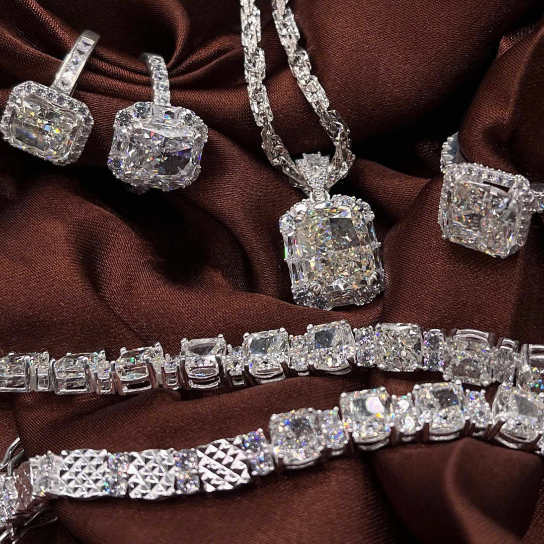 Diamond jewelry set including necklace, earrings, and bracelet on a brown fabric background.