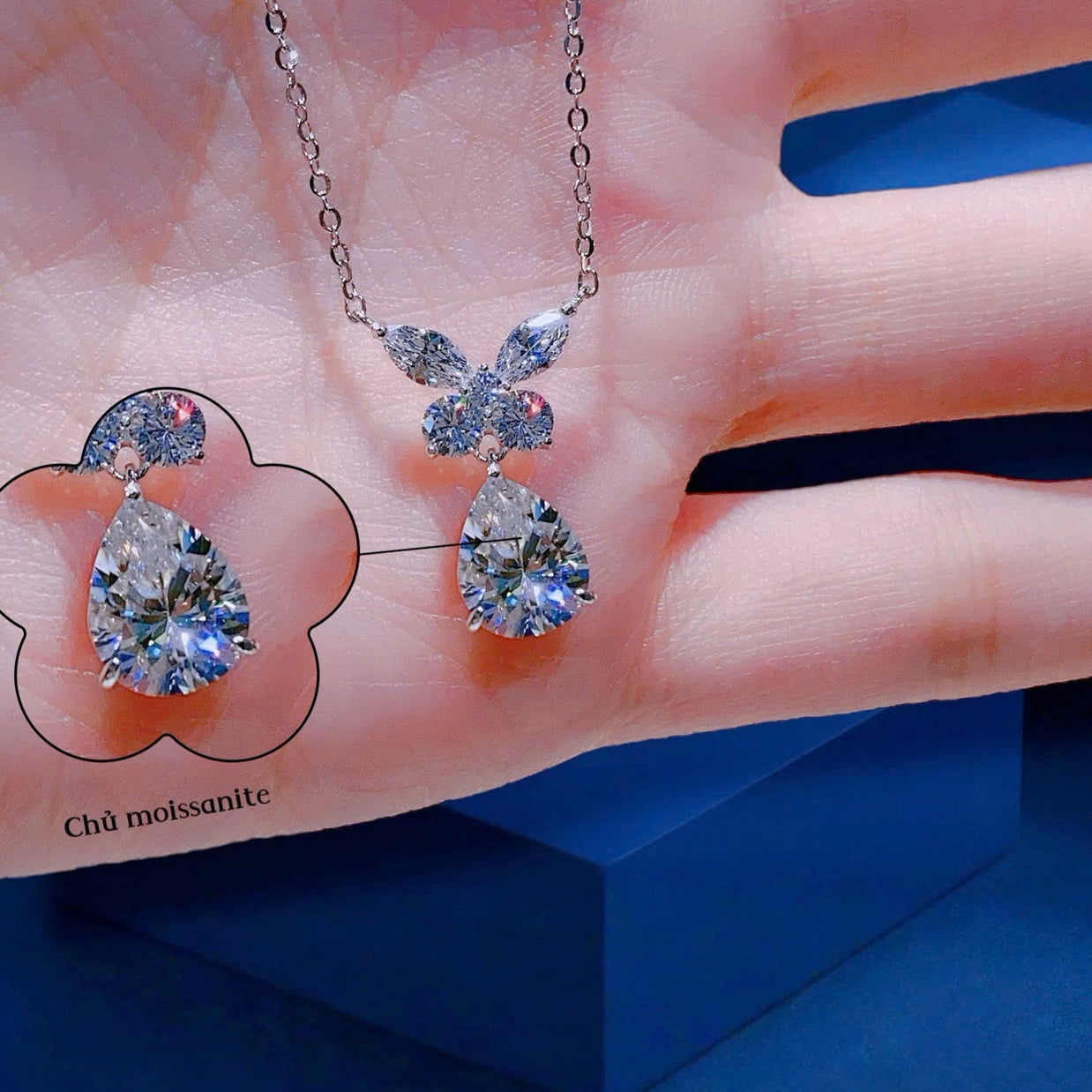 Diamond necklace and earrings on a hand with a blue background