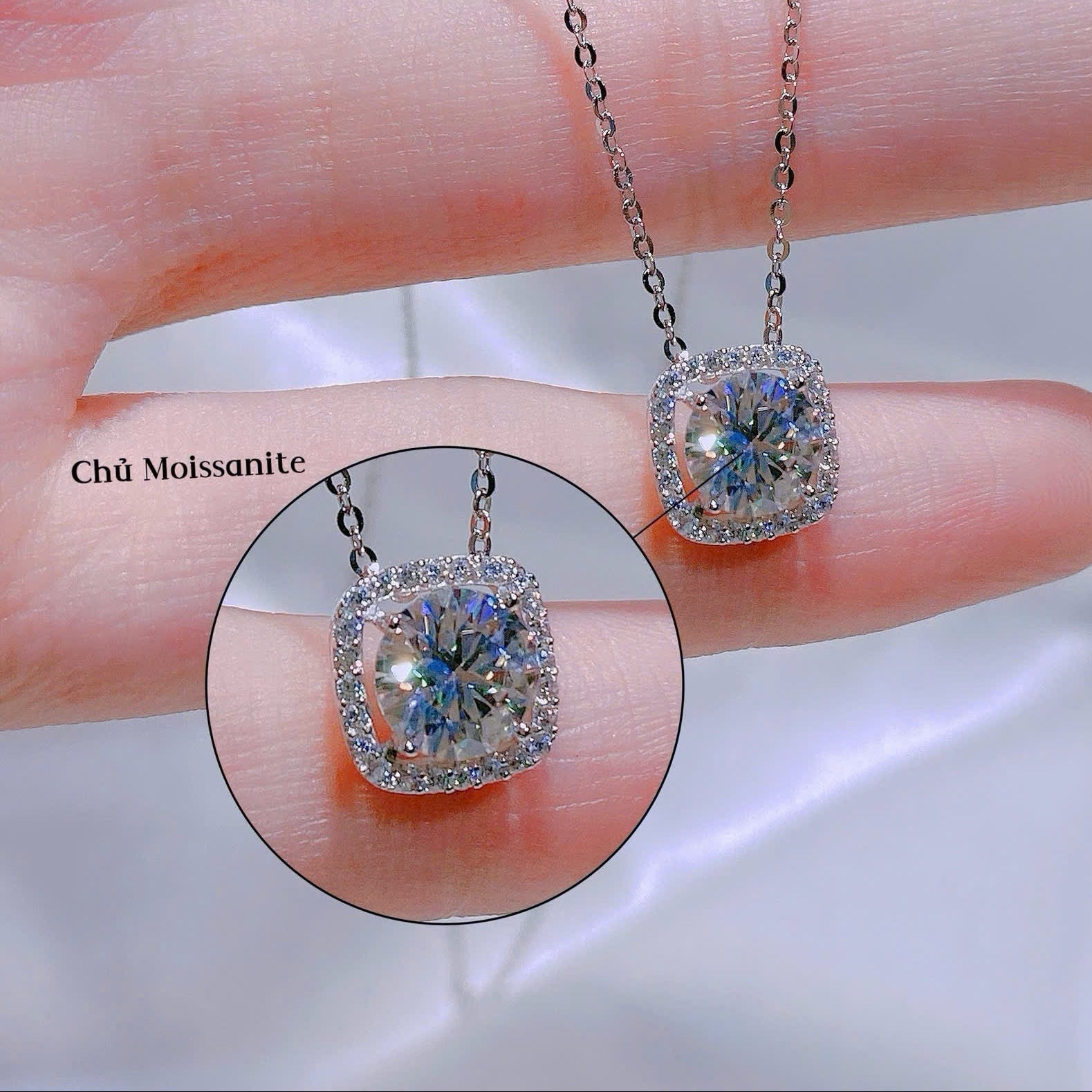 Diamond necklace held between fingers with close-up inset on a blurred background