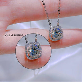 Diamond necklace held between fingers with close-up inset on a blurred background
