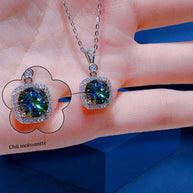 Diamond necklace with green gemstone held in hand against a blue background