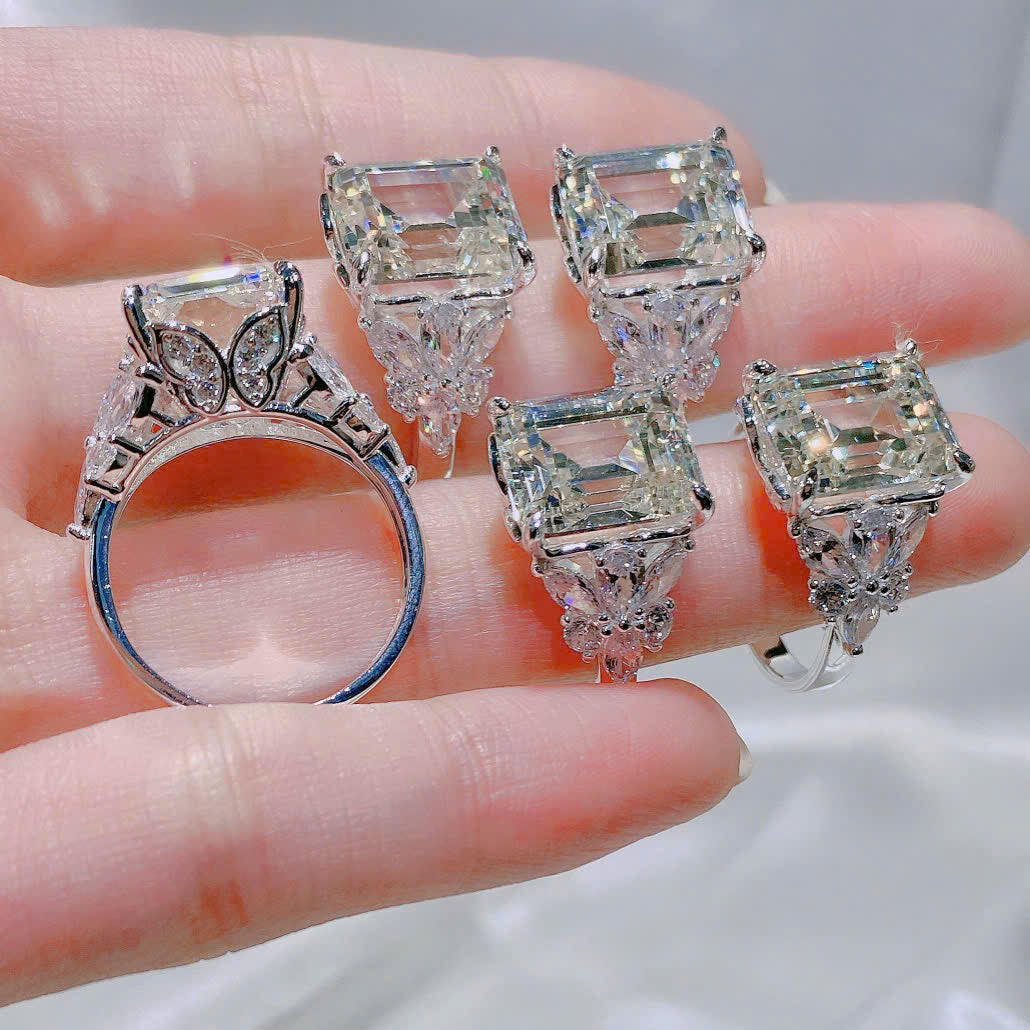 Diamond ring and earrings held in a hand against a neutral background
