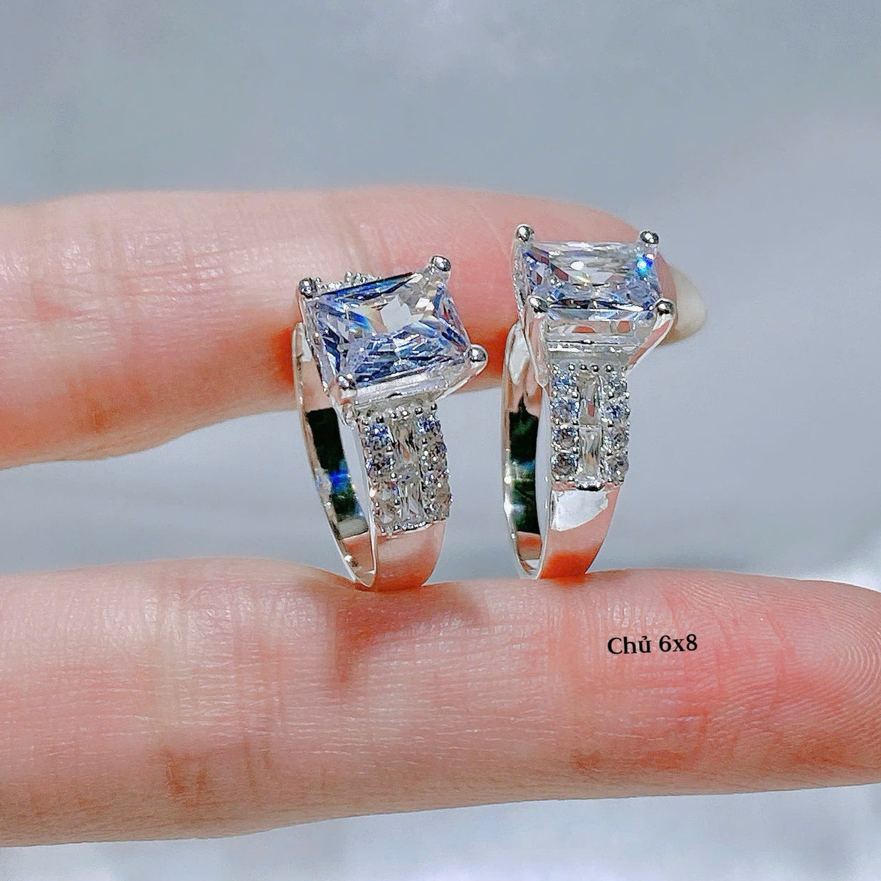 Diamond ring held between fingers with a neutral background