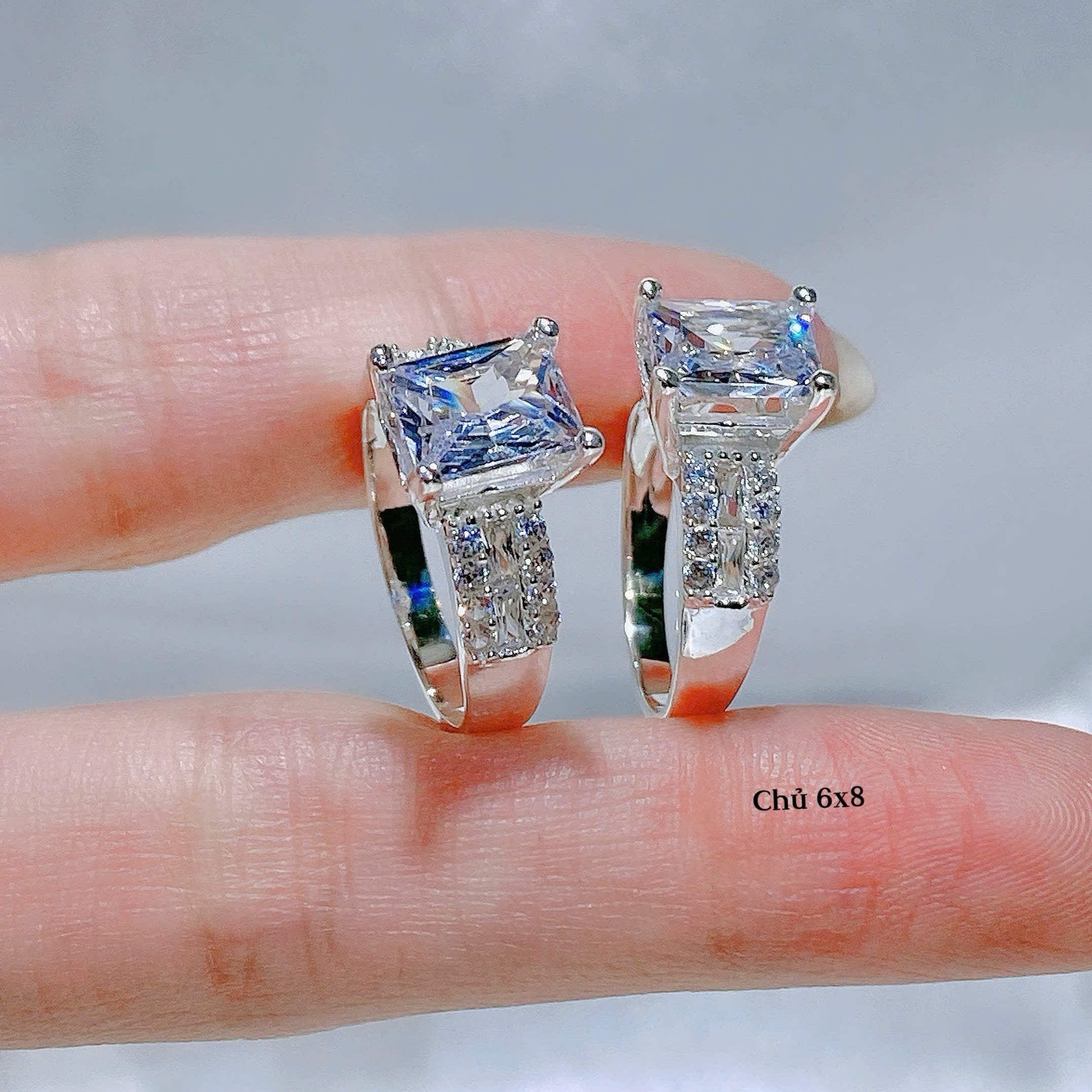 Diamond ring held between fingers with a neutral background