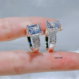 Diamond ring held between fingers with a neutral background