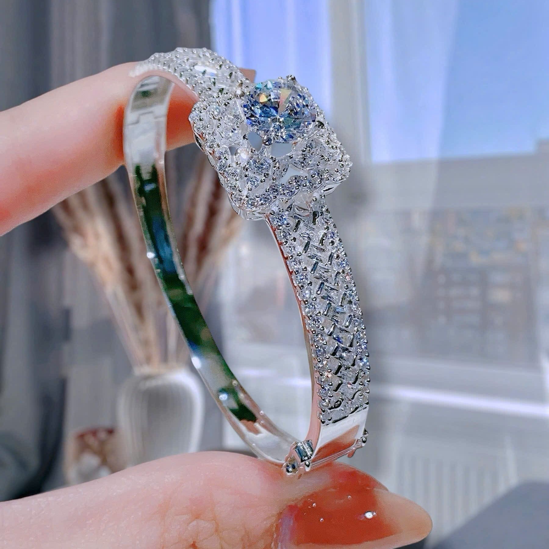 Diamond ring held by a hand with a blurred background