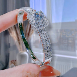 Diamond ring held by a hand with a blurred background