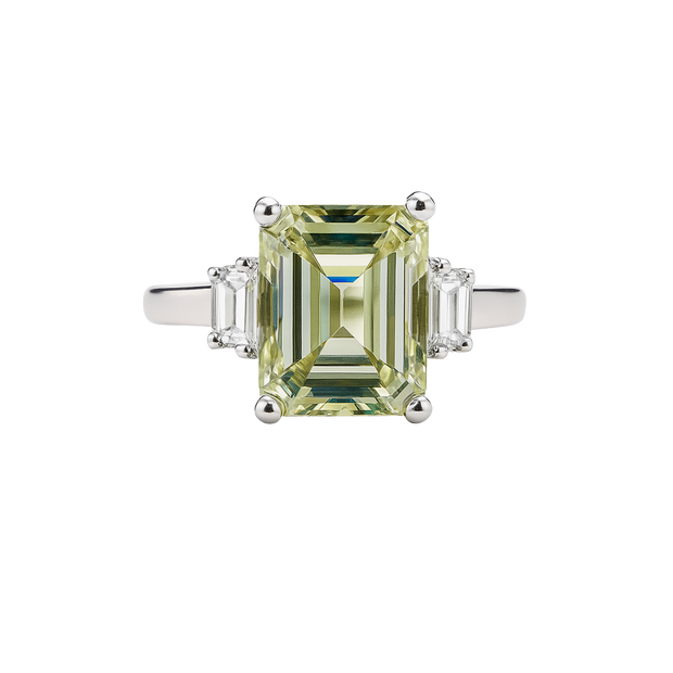 Diamond ring with a green gemstone on a white background