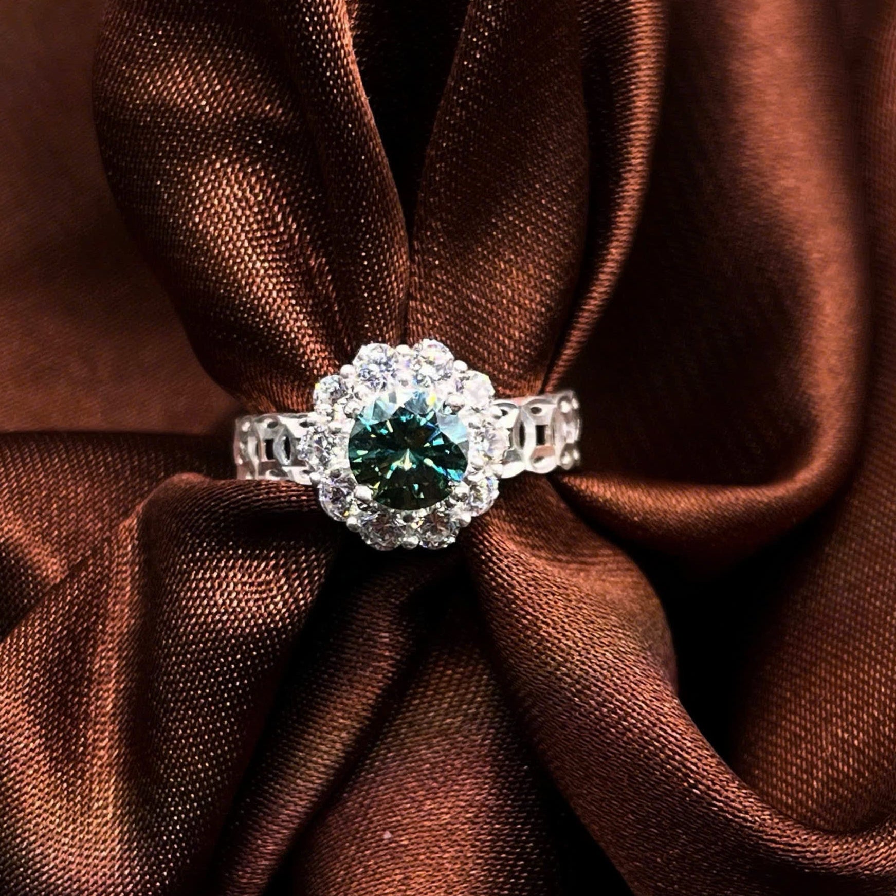 Diamond ring with a green gemstone on brown fabric