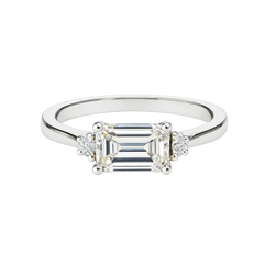 Diamond ring with emerald-cut center stone and smaller side stones on a white background