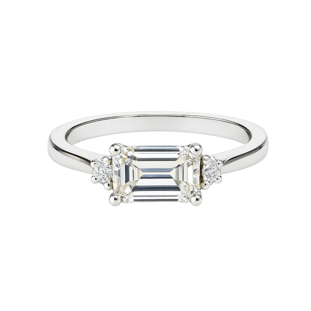 Diamond ring with emerald-cut center stone and smaller side stones on a white background