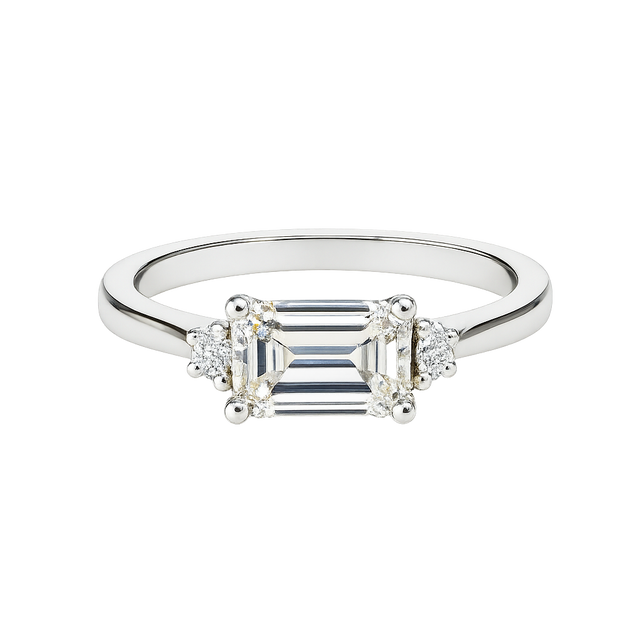 Diamond ring with emerald-cut center stone and smaller side stones on a white background