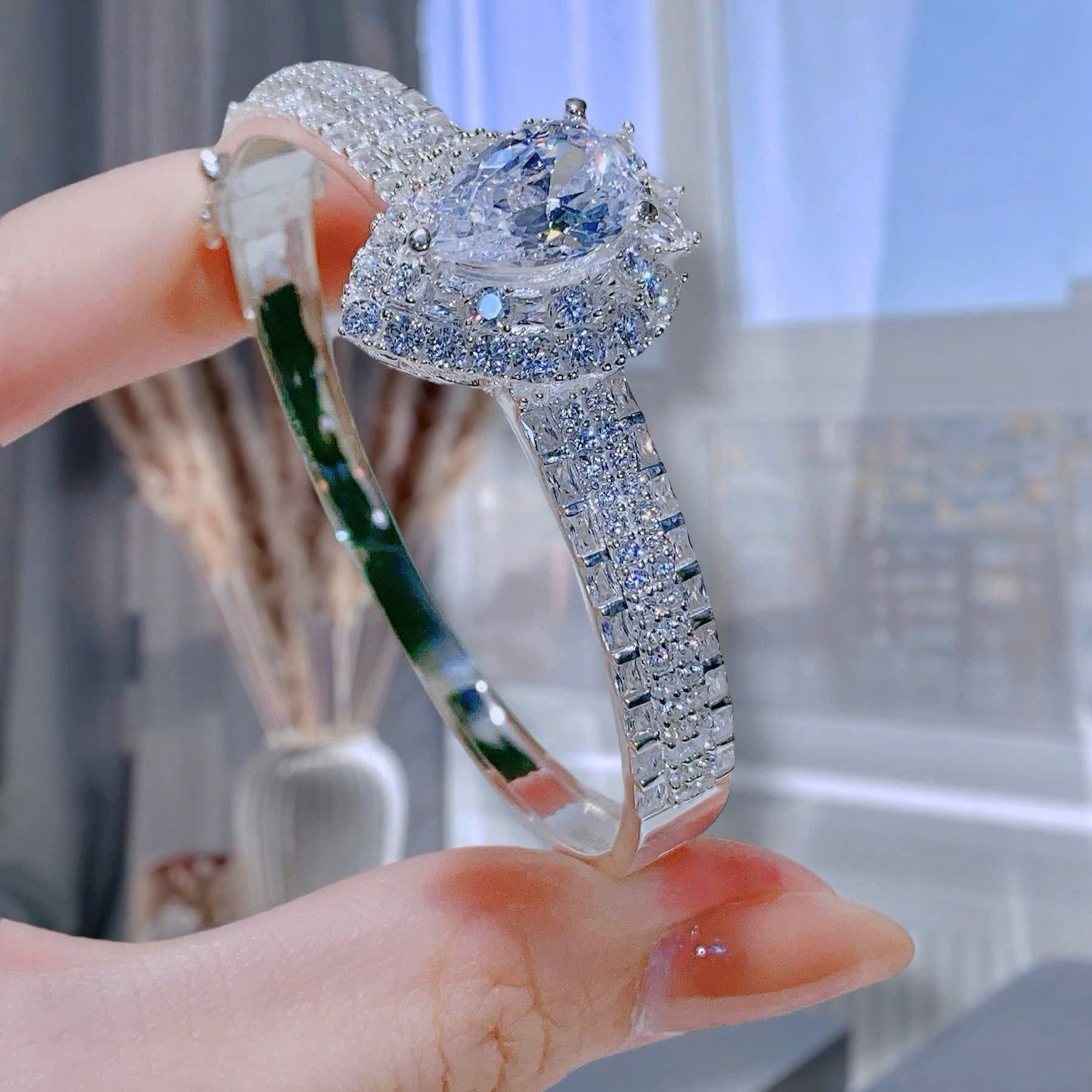 Elegant diamond ring held by a hand with a blurred background