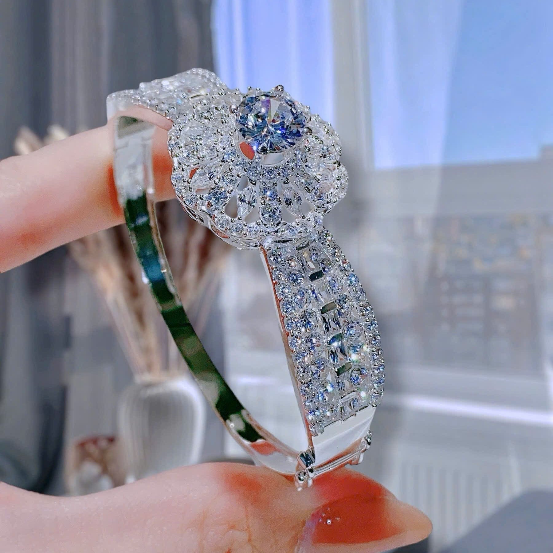 Elegant silver bracelet with a blue gemstone held by a hand.