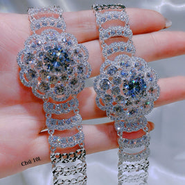 Elegant silver earrings with clear stones held between fingers against a neutral background