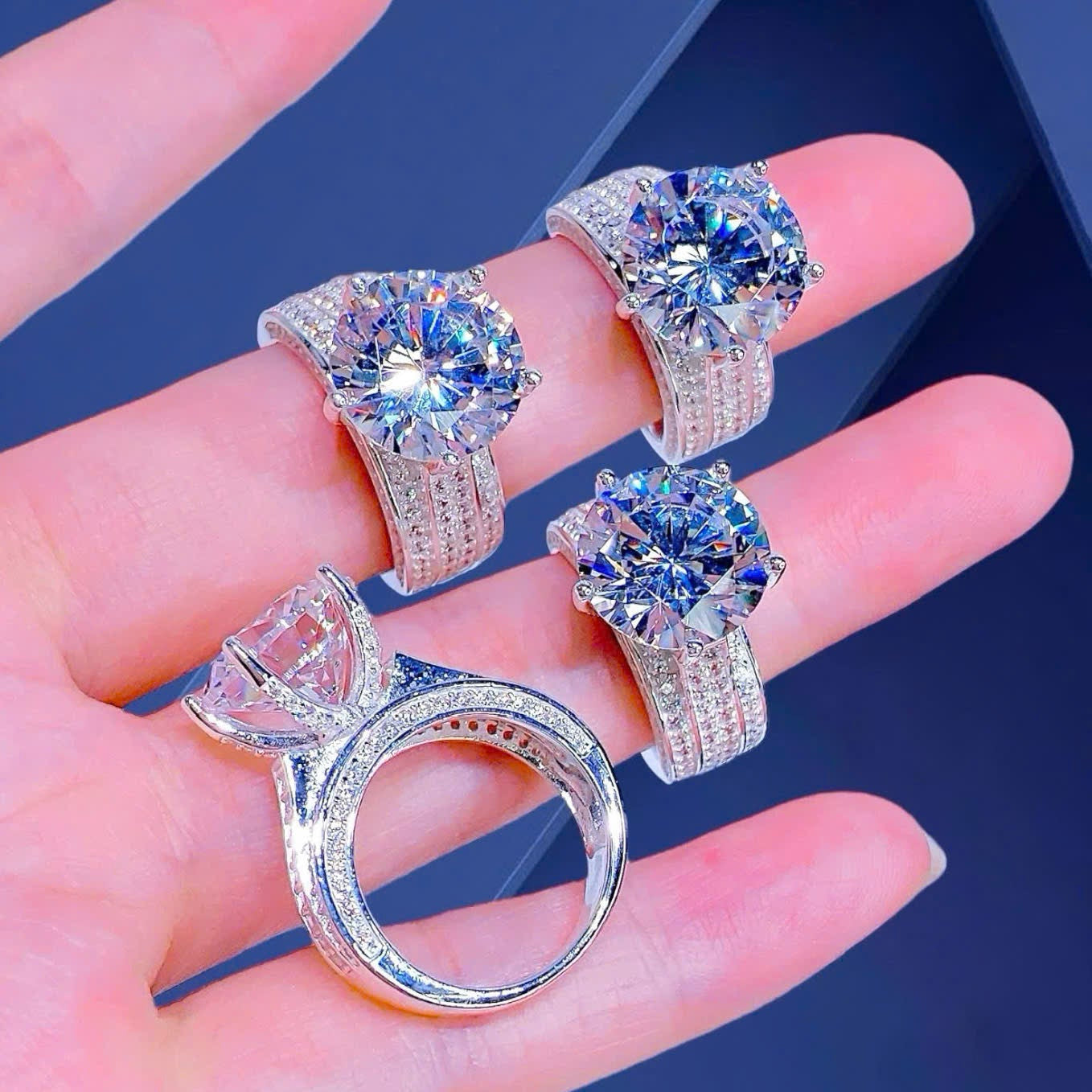 Four diamond rings displayed on a hand against a dark background