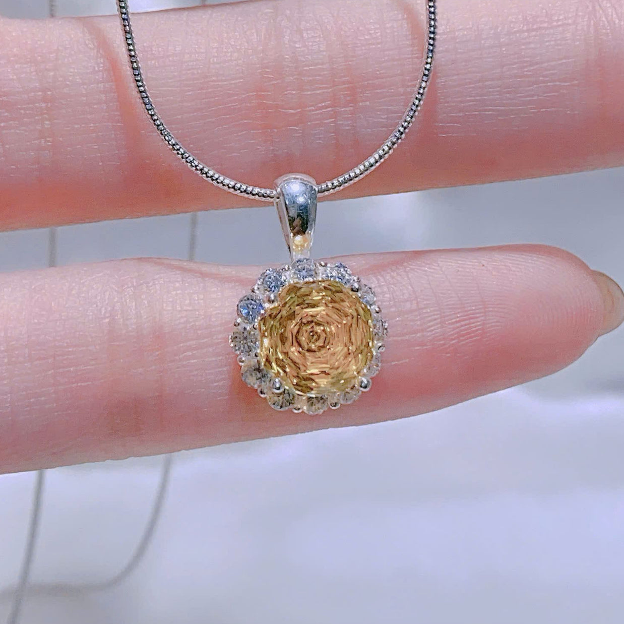 Gold pendant necklace on a hand with a blurred background