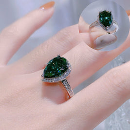 Green gemstone ring on a finger with a blurred background