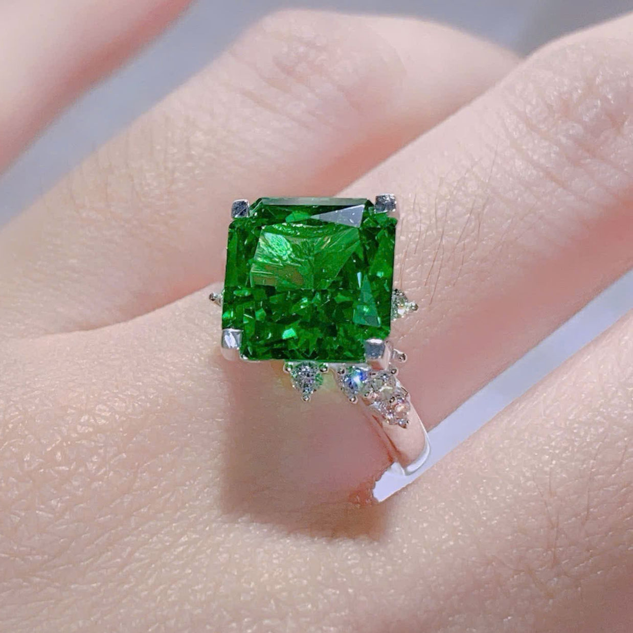 Green gemstone ring on a hand with a blurred background