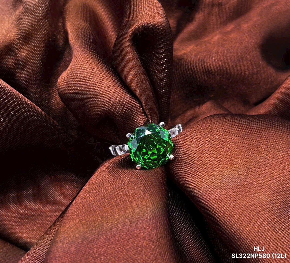 Green gemstone ring on brown fabric
