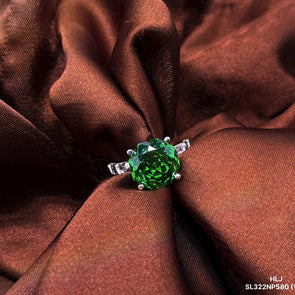 Green gemstone ring on brown fabric