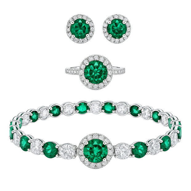 Jewelry set with emerald green gemstones and silver or white gold bands on a white background