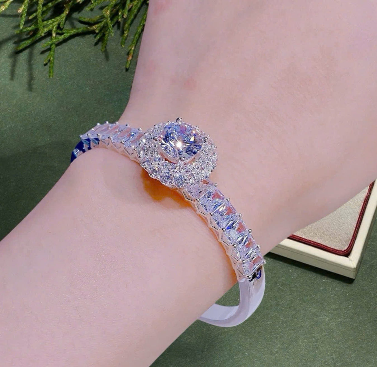 Luxury bracelet with gemstones on a wrist against a green background